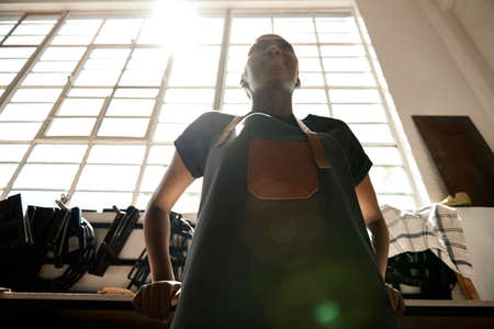 Young African female leather worker standing in her workshop