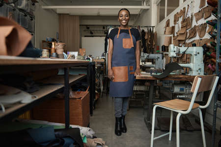 Young African female leather worker standing in her artisanal studioの写真素材