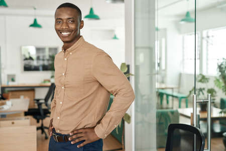 Smiling young African businessman standing alone in an office