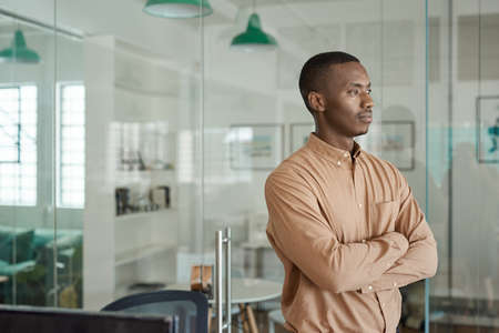 African businessman thinking about work while standing in an officeの写真素材