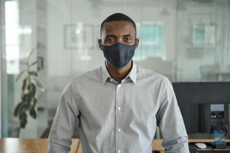 Young African businessman wearing a face mask in an officeの写真素材