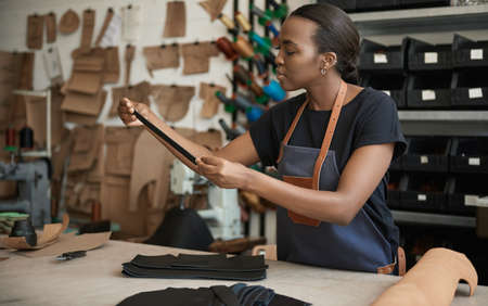 Young African female artisan working in her leather studioの写真素材