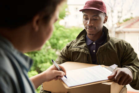 African courier having a customer signer for a deliveryの写真素材