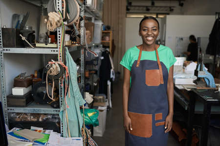 Smiling young African female leather worker standing in her shopの写真素材