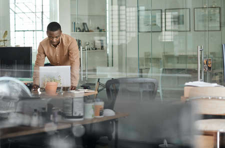 African businessman leaning on his desk and using a laptop