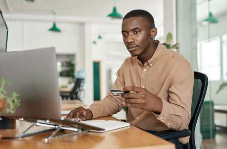 African businessman using a credit card online at his deskの写真素材
