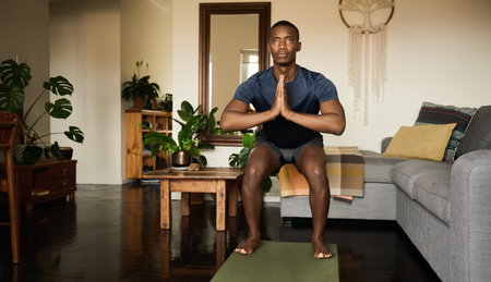 African man in the chair pose while doing yoga at homeの写真素材