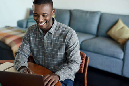 Smiling young African businessman working on a laptop at homeの写真素材