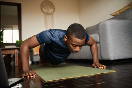 Young African man planking during a yoga session at homeの写真素材