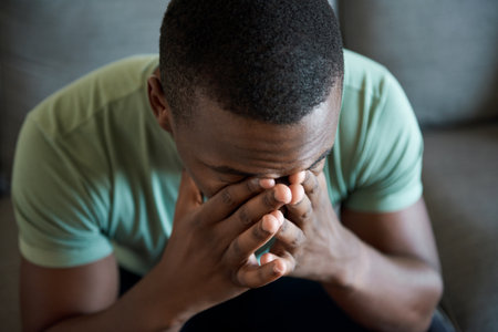 Young African man sitting with his head in his handsの写真素材