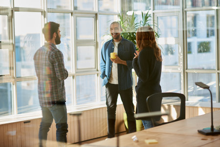 Laughing group of young businesspeople talking inside an office