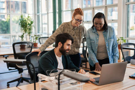 Smiling group of diverse businesspeople working on a laptopの写真素材