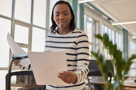 Young African businesswoman reading paperwork at her office deskの写真素材