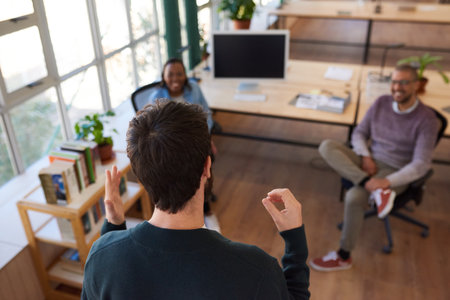 Businessman talking with smiling coworkers during a casual office meetingの写真素材