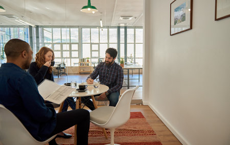 Businesspeople talking together during a casual meeting in an officeの写真素材