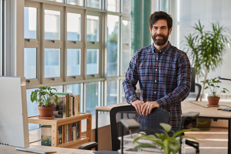 Smiling businessman leaning on a chair in a modern officeの写真素材