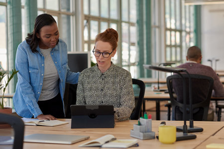 Two diverse businesswomen working on a tablet together in an officeの写真素材