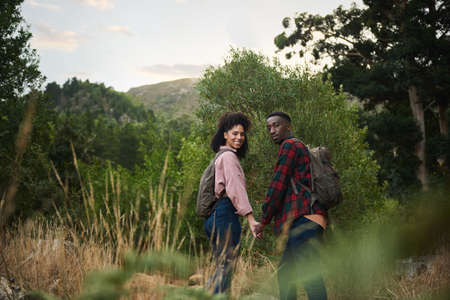Smiling young multiethnic couple out for a hike together in some hillsの写真素材