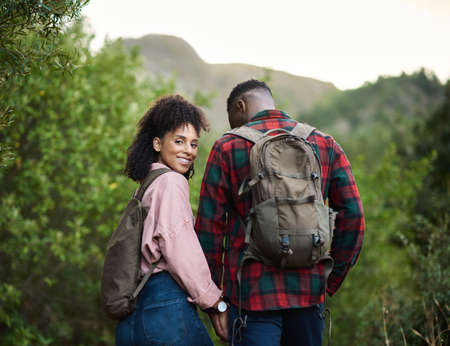 Smiling young multiethnic couple hiking hand in hand outdoorsの写真素材
