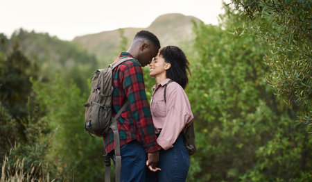 Loving multiethnic couple standing with closed eyes on a hiking trailの写真素材
