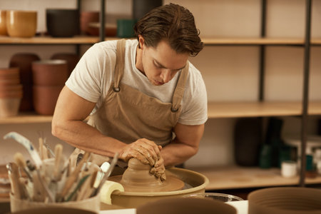 Ceramist shaping clay spinning on a wheel in a ceramic studioの写真素材