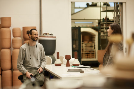 Smiling ceramics studio owner and a colleague discussing designsの写真素材