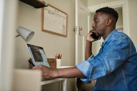African businessman talking on a phone while working from homeの写真素材