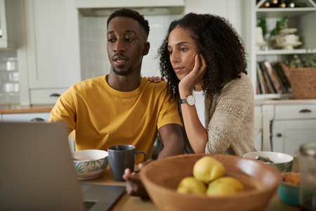 Young multiethnic couple using a laptop while having breakfastの写真素材