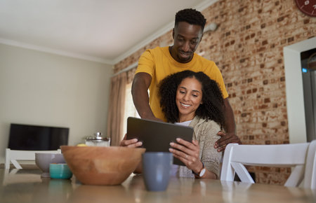 Smiling young multiethnic couple using a tablet together in the morningの写真素材