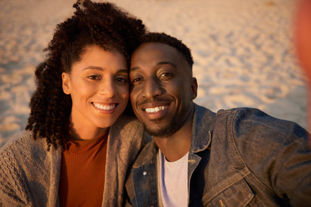 Smiling young multiethnic couple taking a selfie on a sandy beachの写真素材