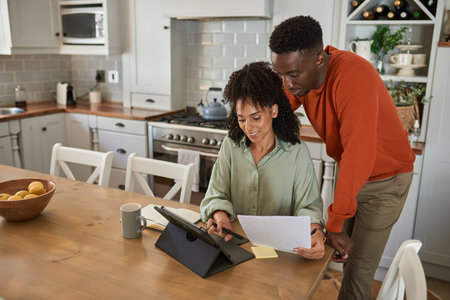 Smiling multiracial couple doing their online banking on a tabletの写真素材