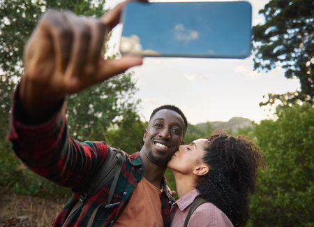 Young multiethnic couple smiling and taking a selfie during a hikeの写真素材
