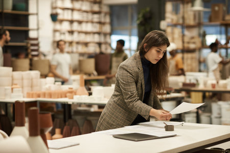 Ceramics studio manager signing paperwork at a tableの写真素材