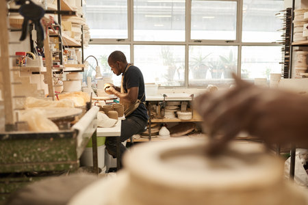 African potter working on a bowl at a bench in a ceramics studioの写真素材