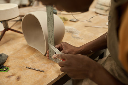 African ceramist measuring a pot at a bench in a workshopの写真素材