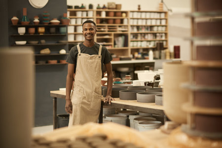 Smiling young African potter working in a large ceramics workshopの写真素材