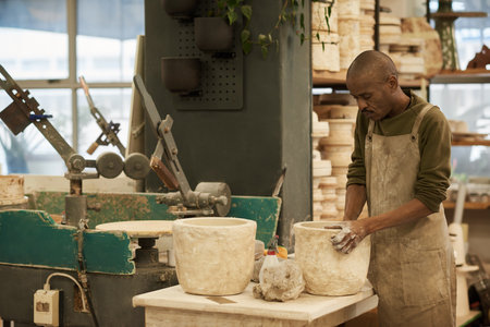 African ceramist cleaning molds at a pottery studio workbench