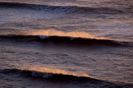 series of waves breaking a sunsetの写真素材