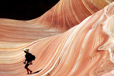 woman in cowboy hat running down wave of sandstoneの写真素材