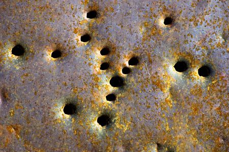 detail of pattern of bullet holes in rusted metal car doorの写真素材