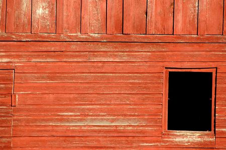 detail of faded red barn siding with black hole in right frameの写真素材