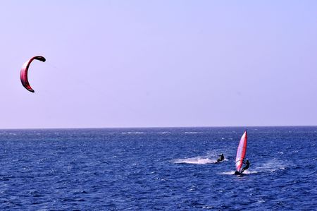 kite boarder and windsurfer side by side on caribbean blue seaの写真素材