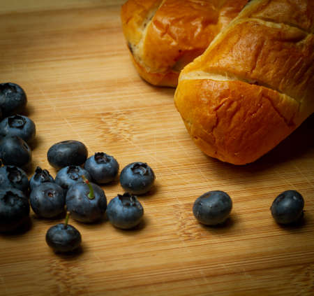blueberries with small sweet bakes all shown on bamboo cutting boardの写真素材