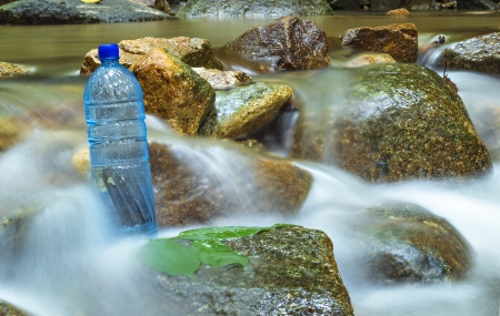 cold stream at tropical forest with fresh mineral bottleの写真素材