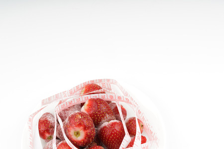 Frozen strawberries with tape measurement with white background. Diet concept.の写真素材