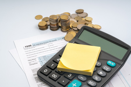 1040 tax form with coins and calculator