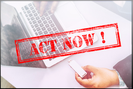 Hand with red grunge stamp with text "ACT NOW". Technology concept.の写真素材