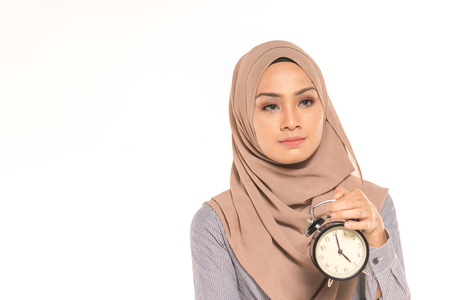 A pretty student holding clock. Time management concept.の写真素材