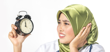 Veiled medical staff with clock. Time management concept.の写真素材