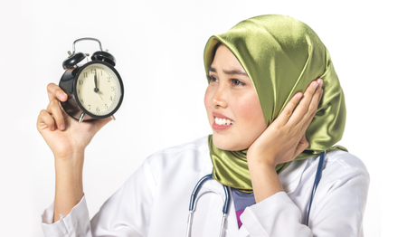 Veiled medical staff with clock. Time management concept.の写真素材